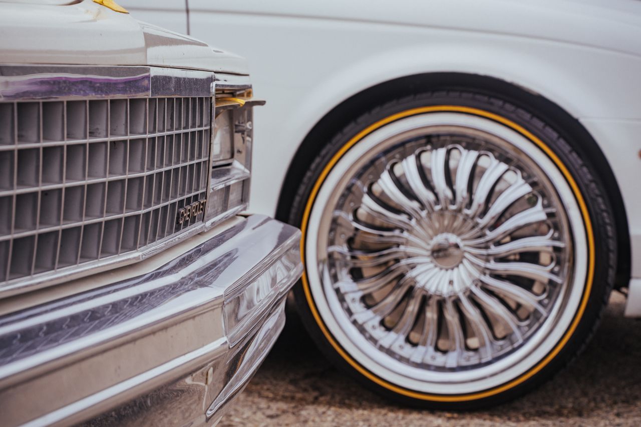 Detailed view of vintage car front grille and custom wheel in focus.