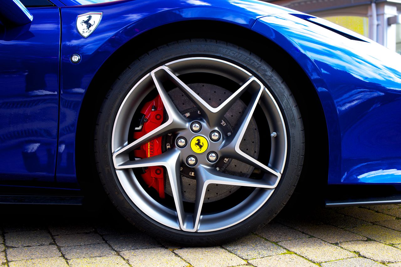 Detailed shot of a blue sports car wheel and emblem in the UK.